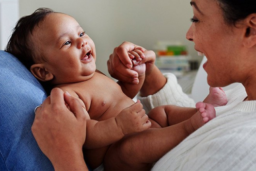 A laughing mother holding a baby on her lap